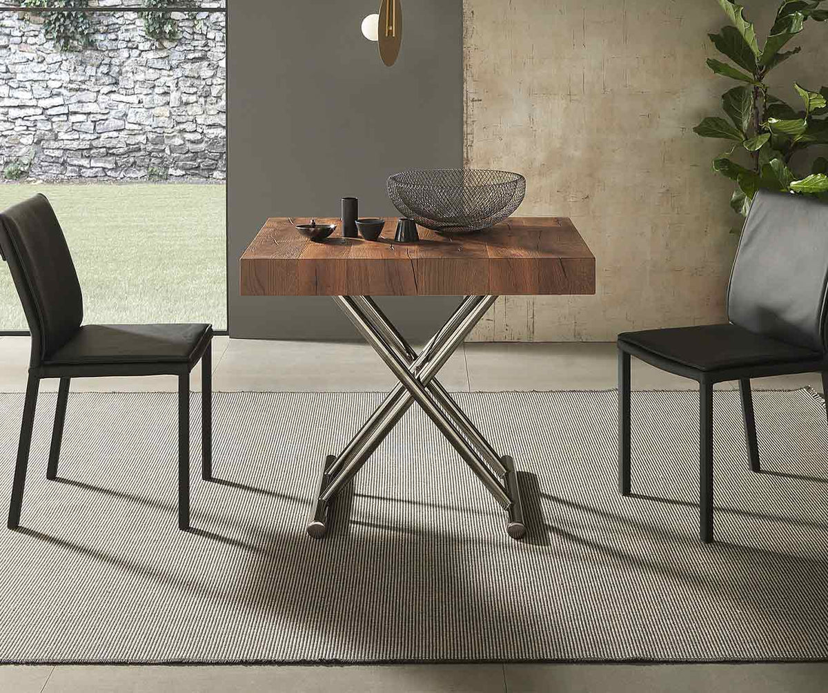 Table extensible CALYPSO Bois Massif Termotrattato avec plateau en bois massif finition naturelle, associée à un pied en métal moderne et deux chaises noires pour un espace repas contemporain.
