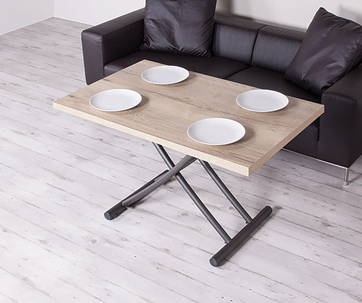 Table basse relevable en GENIALE Mélaminé Nodato, avec plateau en bois clair et pieds en métal noir, disposée devant un canapé en cuir noir avec quatre assiettes blanches dessus.