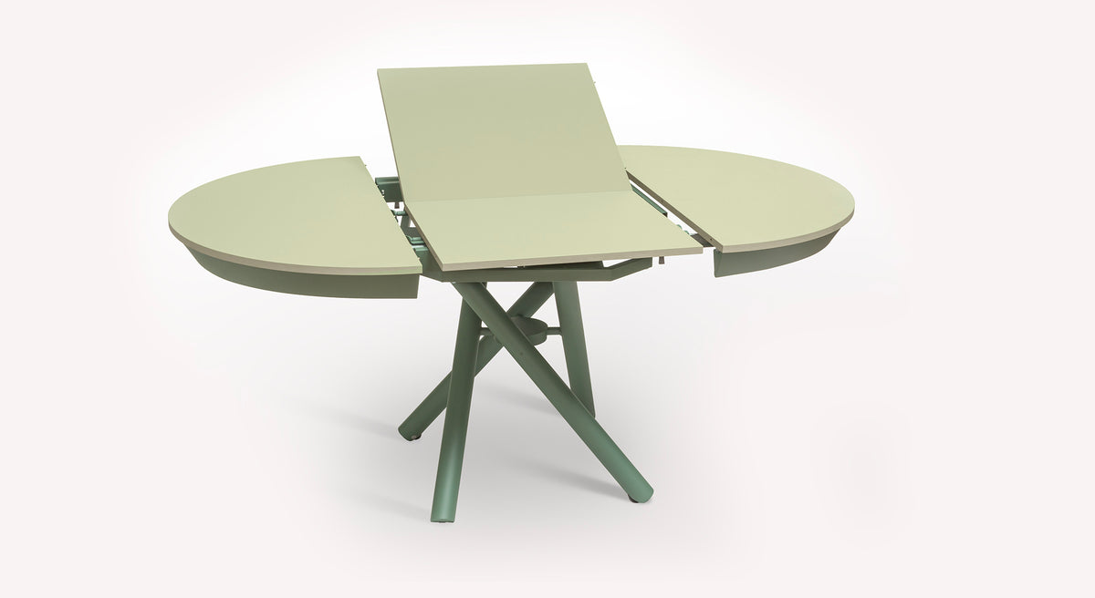 Table extensible Helios avec plateau central déployé, pieds croisés verts, design moderne et fonctionnel