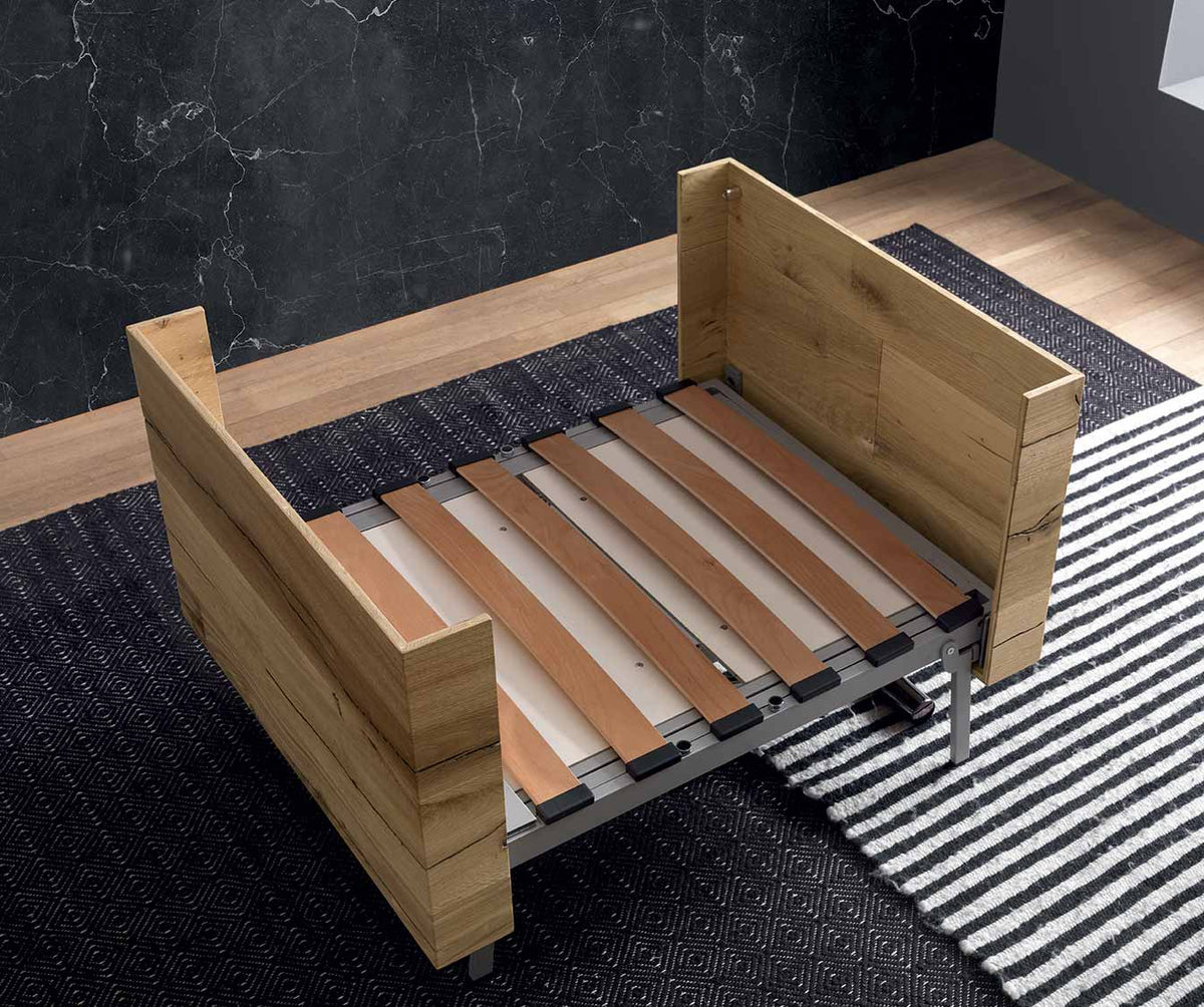 Structure en bois clair semi-ouverte d'une table extensible, mise en scène sur tapis avec design moderne, modèle TAVOLETTO +50 coloris & matériaux.