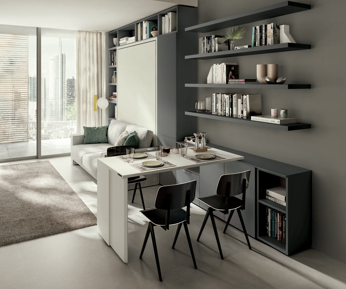 Espace de vie contemporain avec canapé gris, table extensible blanche et chaises noires, intégré dans un mur avec étagères et rangements, présenté avec GIRO +50 coloris & matériaux.