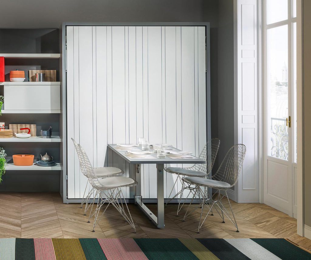 Table escamotable contemporaine déployée dans un espace lumineux avec chaises en métal et coussins, illustrant parfaitement la fonctionnalité et l’esthétique de PENELOPE DINING +50 coloris & matériaux.