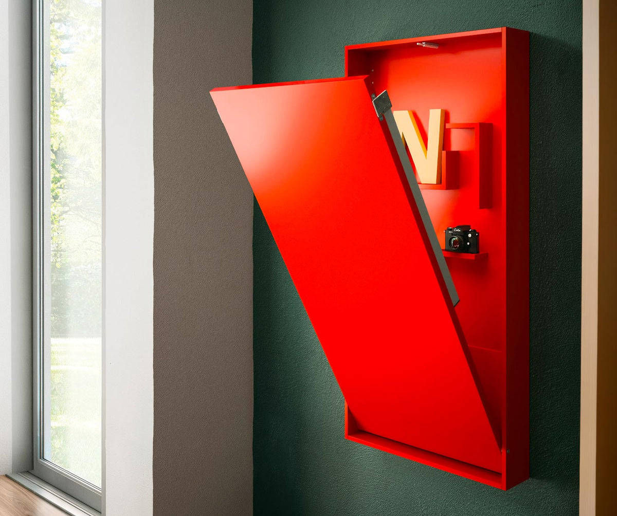 Bureau WALLY +50 coloris & matériaux rouge semi-ouvert fixé sur un mur vert, avec rangement intérieur et vue partielle du mécanisme d'ouverture, près d'une large fenêtre.