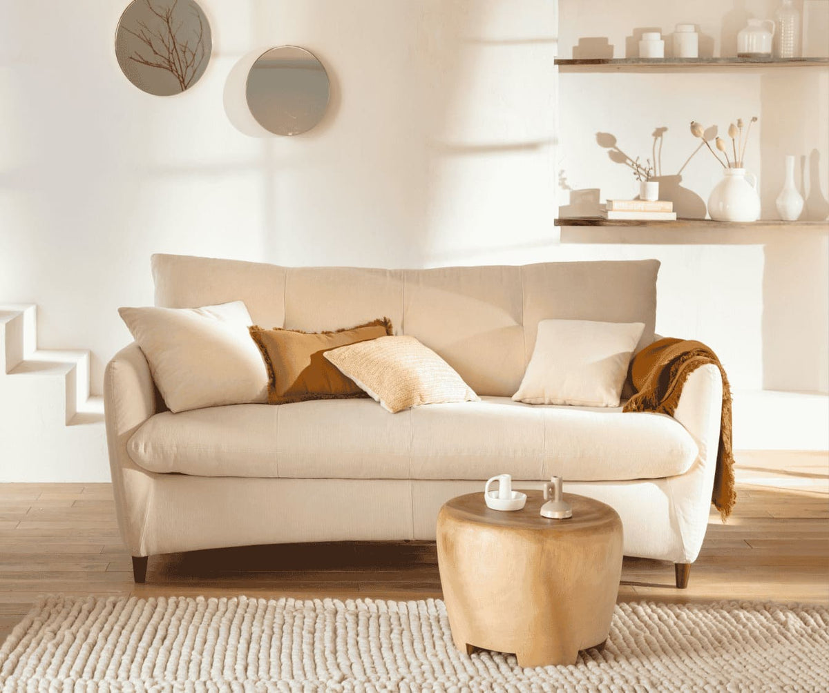 Canapé convertible BOW Mariclo Etain en tissu beige, décor minimaliste avec coussins et plaid, ambiance chaleureuse et contemporaine dans un salon lumineux.