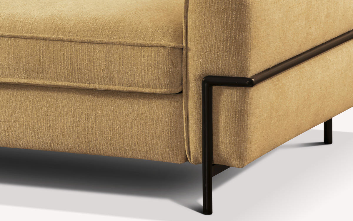 Coin d'un canapé convertible en tissu curcuma avec structure métallique noire
