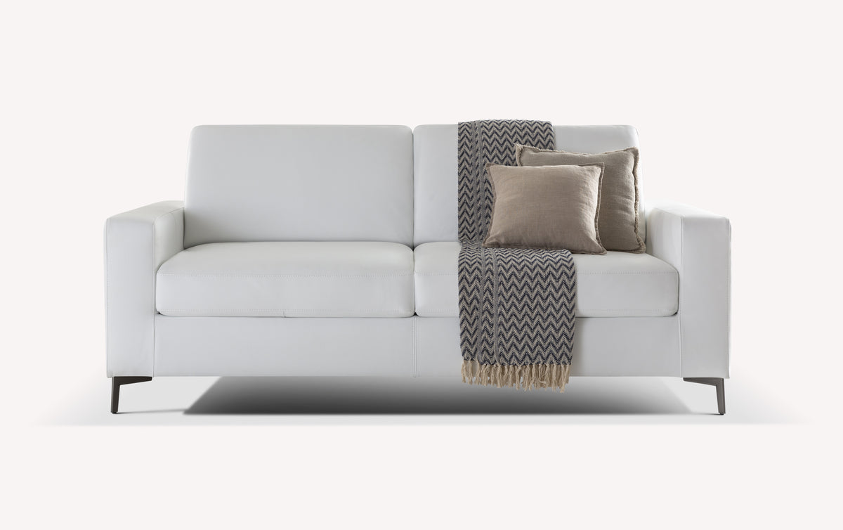 Canapé convertible Lisbona en cuir blanc avec coussins beiges et plaid à motifs chevrons