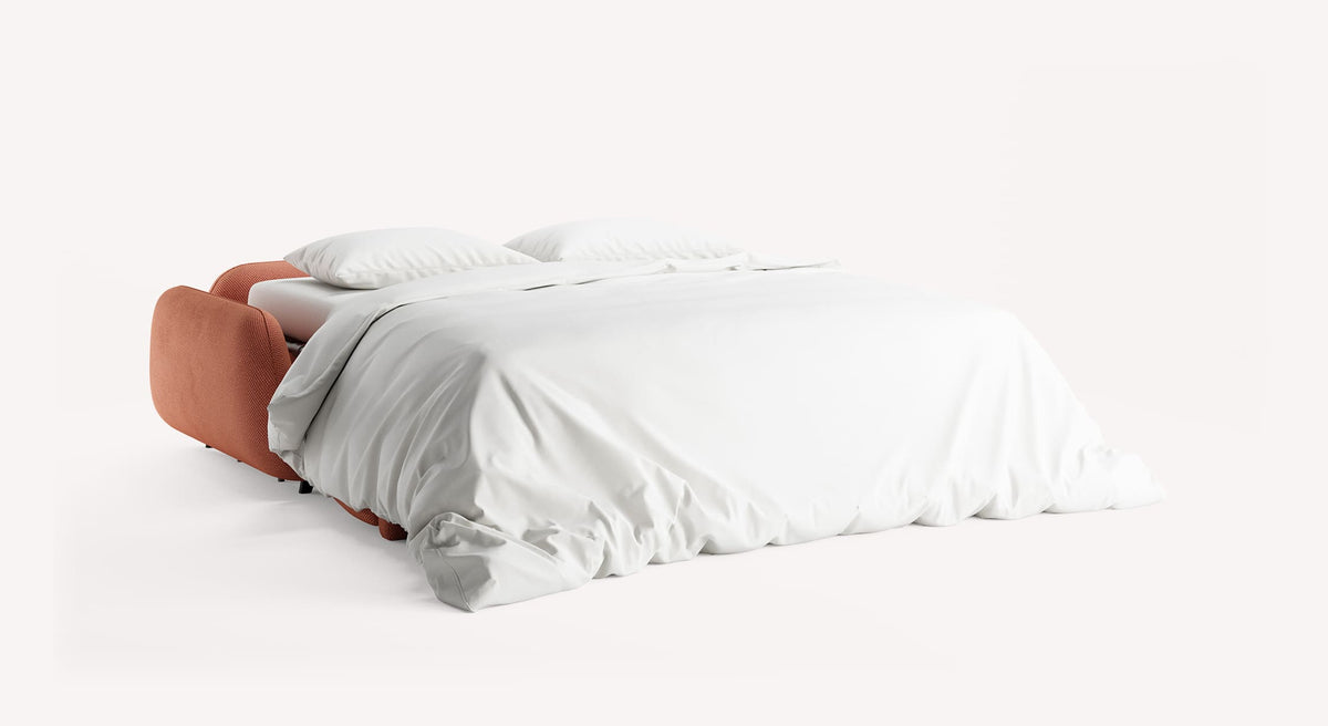 Canapé convertible MOON Moby Corail avec couchage quotidien déplié, draps blancs et deux oreillers, design moderne et confortable adapté pour un lit d’appoint.