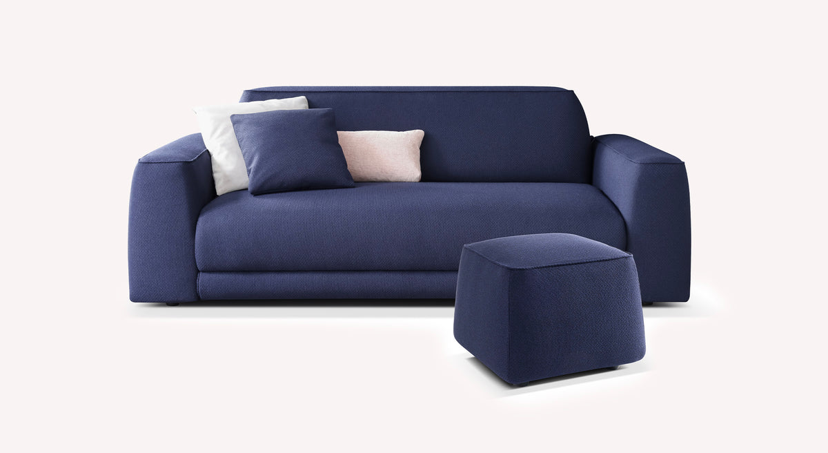 Lot canapé et pouf ONYX en tissu bleu profond avec design moderne, accompagné de coussins pour un confort optimal dans un espace de vie contemporain.