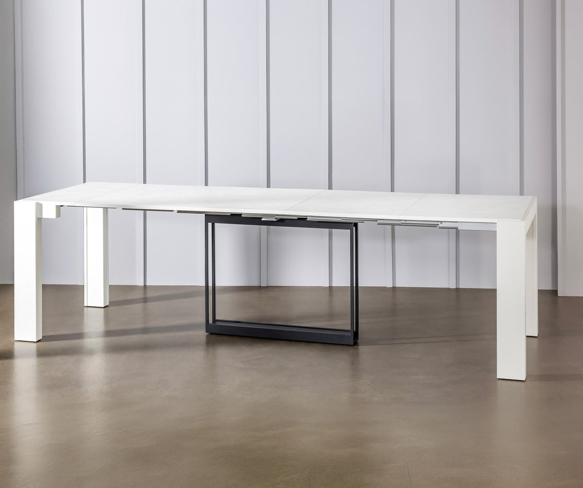 Table extensible moderne ouverte avec plateau blanc et structure noire, modèle COMPACT Mélaminé Bianco spatolato dans un intérieur minimaliste et épuré.