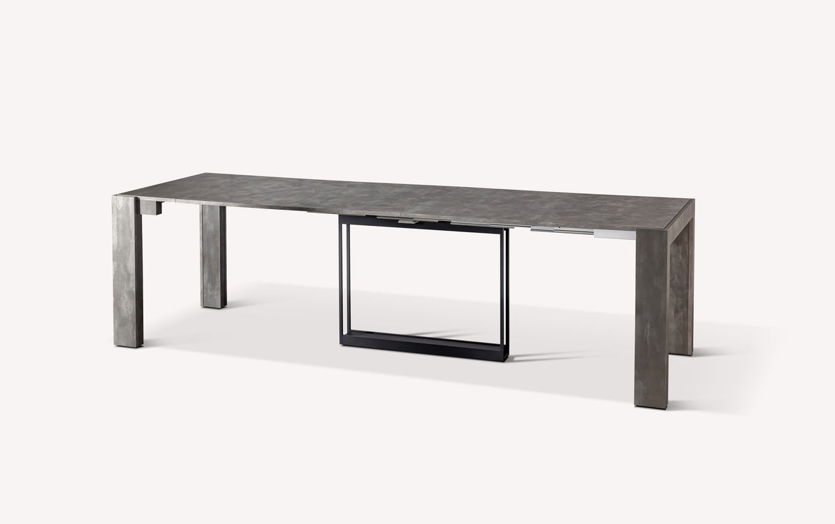 Table extensible compacte en métal gris, ouverte, avec un design moderne et minimaliste