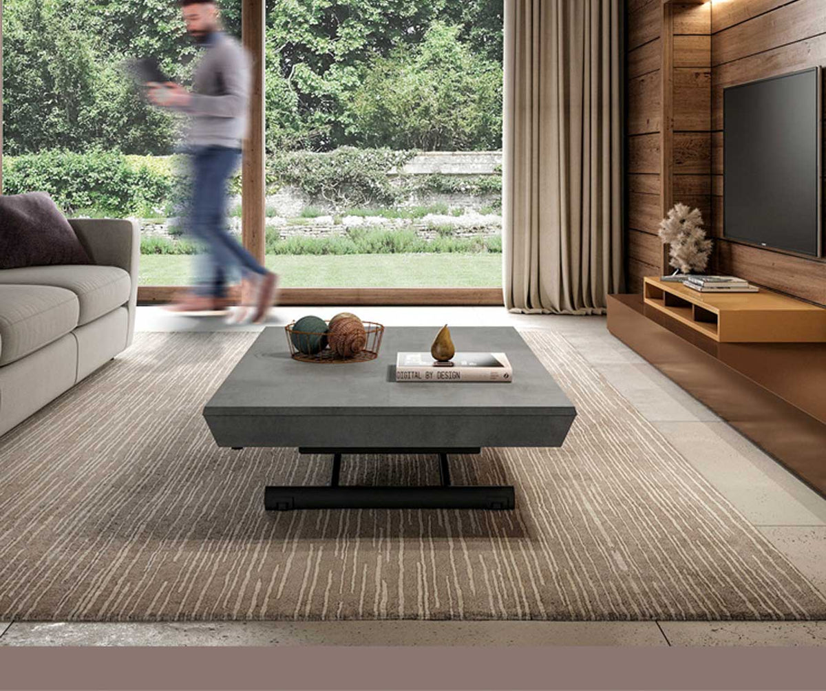 Table basse design en PIU PIU Mélaminé Pietra au centre d’un salon moderne avec canapé, tapis et baie vitrée sur jardin verdoyant.