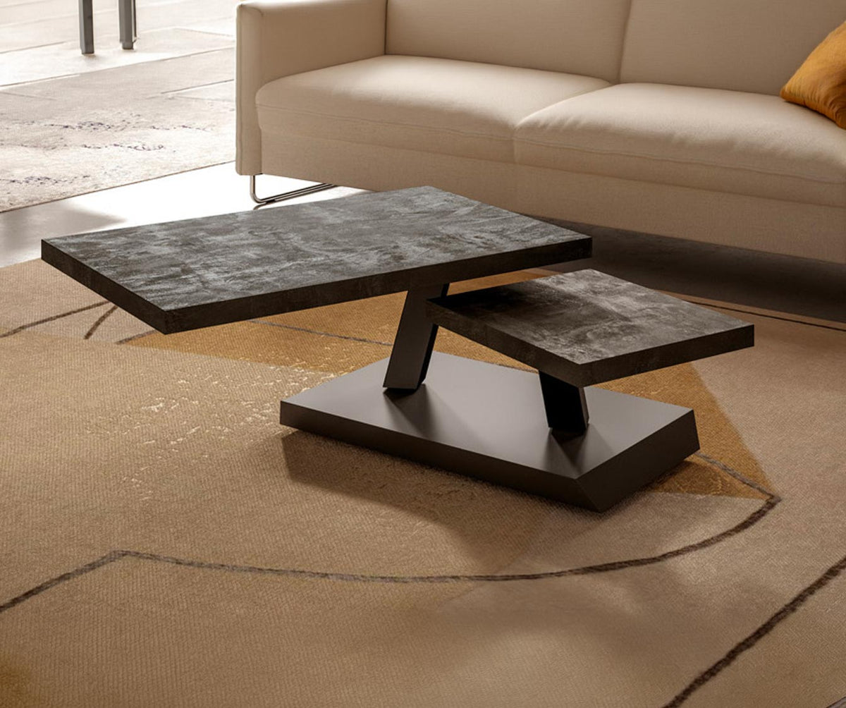 Table basse design RUMBA Mélaminé Vecchio antico avec plateau noir texturé sur piètement incliné, posée sur un tapis beige devant un canapé clair dans un salon moderne.