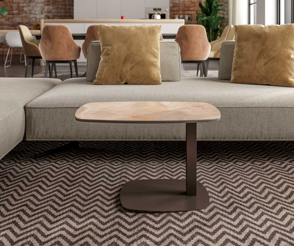Table basse moderne avec plateau en SERVUS Verre Marbré Onice lucido, finition brillante, posée sur un tapis à motifs géométriques dans un salon contemporain.