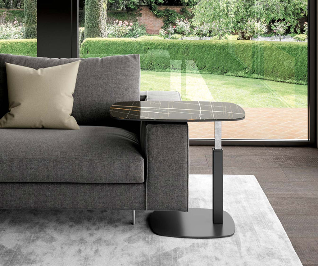 Table d'appoint avec plateau en SERVUS Verre Marbré Sahara noir lucido, posée à côté d'un canapé gris dans un salon contemporain avec vue sur jardin.