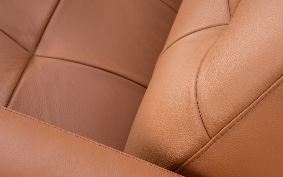 Gros plan sur le cuir cognac du canapé convertible Clark, revêtement lisse et coutures visibles
