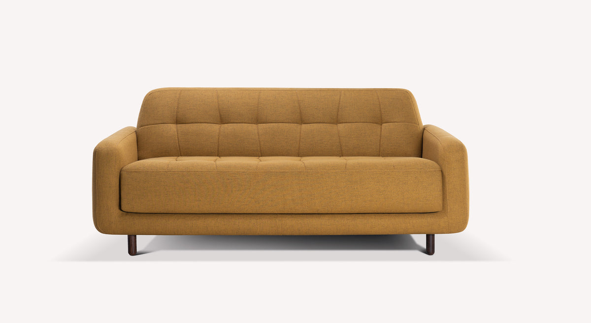 Canapé Clark en tissu curcuma avec pieds en bois, design moderne et capitonnage discret