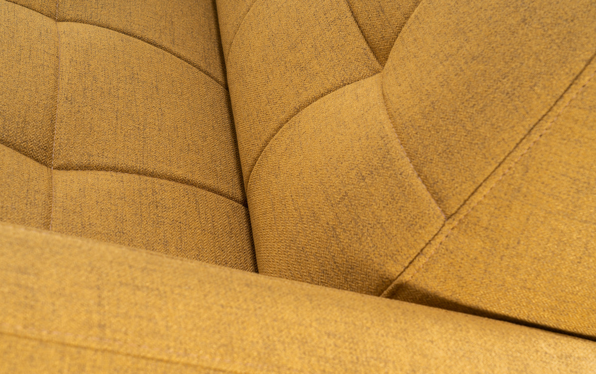 Gros plan sur le tissu jaune curcuma du canapé convertible Clark, montrant des coutures et une revêtement en relief