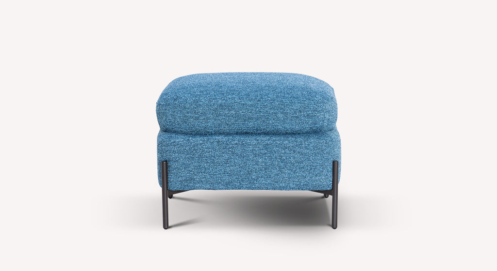 Pouf en tissu bleu denim avec pieds métalliques noirs, design moderne et compact