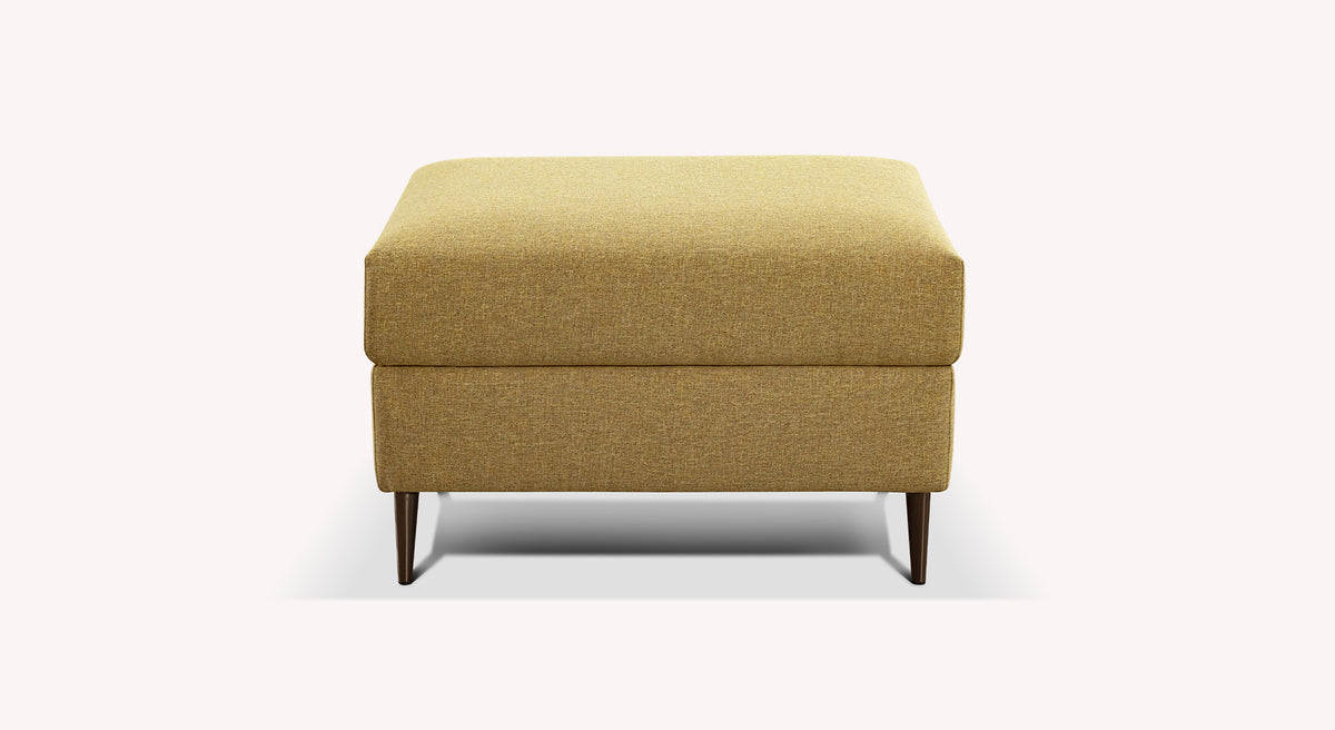 Pouf rectangulaire en tissu jaune moutarde, modèle Layne, avec pieds en bois foncé, sur fond blanc
