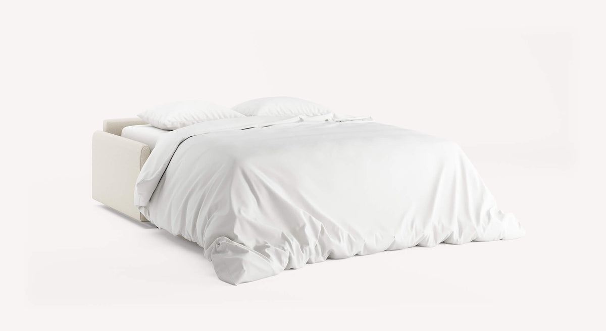 Canapé convertible NELLY Innuendo Ivoire ouvert en lit, draps blancs et oreillers assortis, élégant et moderne pour un couchage quotidien confortable.