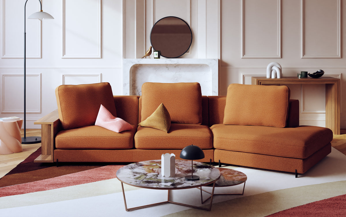 Canapé d'angle en tissu cuivre avec coussins colorés, table basse en marbre, et ambiance élégante dans un salon moderne