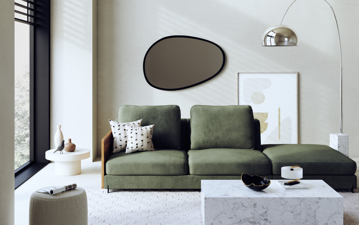 Canapé vert en velours dans un salon moderne avec miroir organique, lampe arquée et table basse en marbre. Ambiance élégante et contemporaine