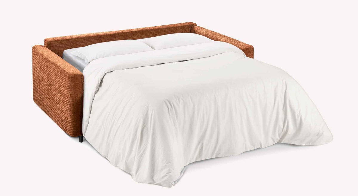 Canapé convertible MOTUS Paradoxe Cuivre déplié en lit avec un matelas confortable, draps blancs et couleur cuivre élégante.