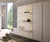 Espace de vie moderne avec armoire-lit blanc LUCY BOOK Mélaminé Blanc intégrant des étagères décoratives sur un panneau à motif floral doré, décoré d’objets design.