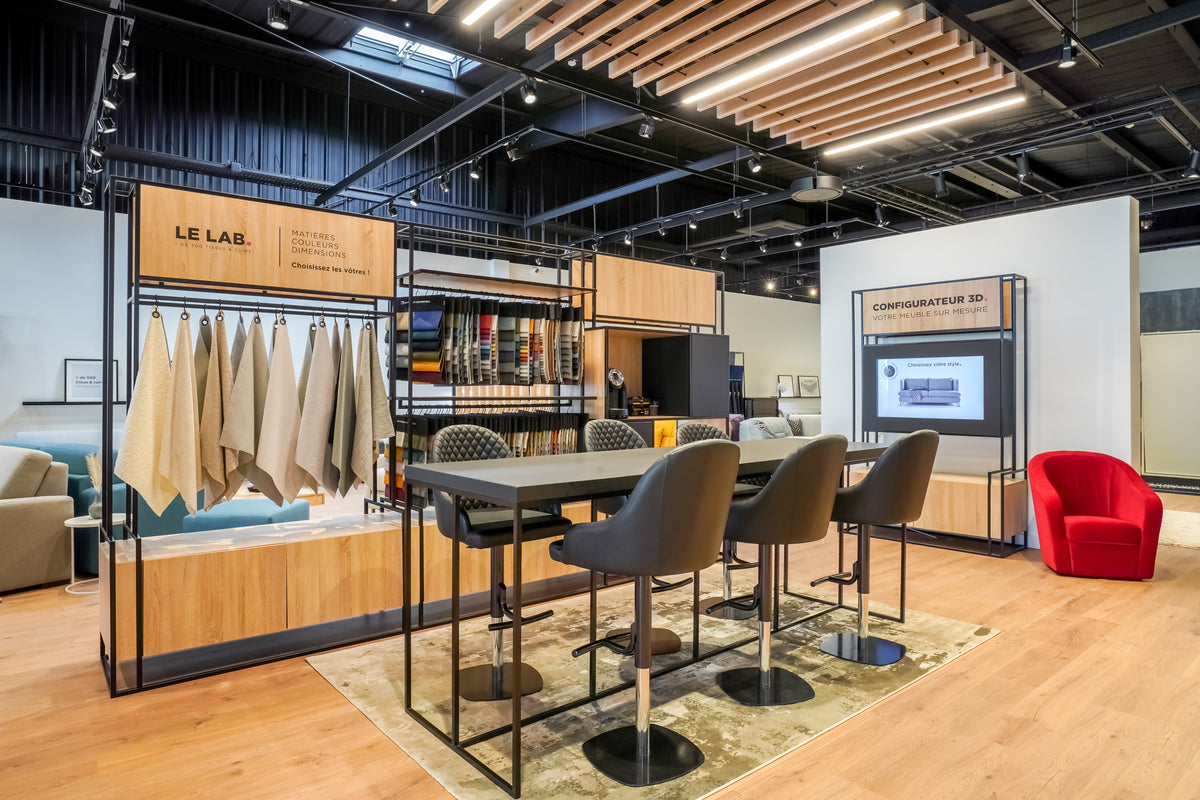 Intérieur moderne de la Tissutheque Croix Blanche avec échantillons de tissus, table haute et configurateur 3D pour meubles sur mesure