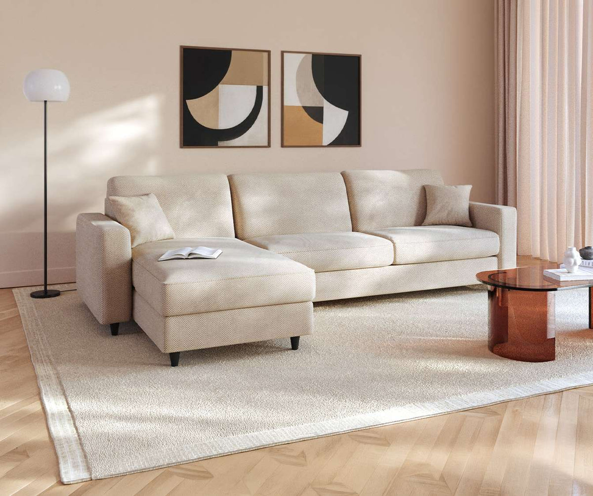 Canapé convertible ALBA Angle Moby Ivoire dans un salon lumineux, avec tapis clair, table basse en verre teinté et décoration murale moderne.