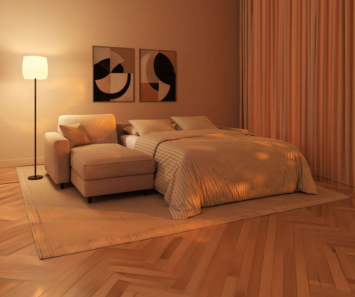 Canapé convertible ALBA Angle Moby Ivoire ouvert en couchage, dans une chambre chaleureuse avec parquet chevron, tapis beige et lampadaire moderne.