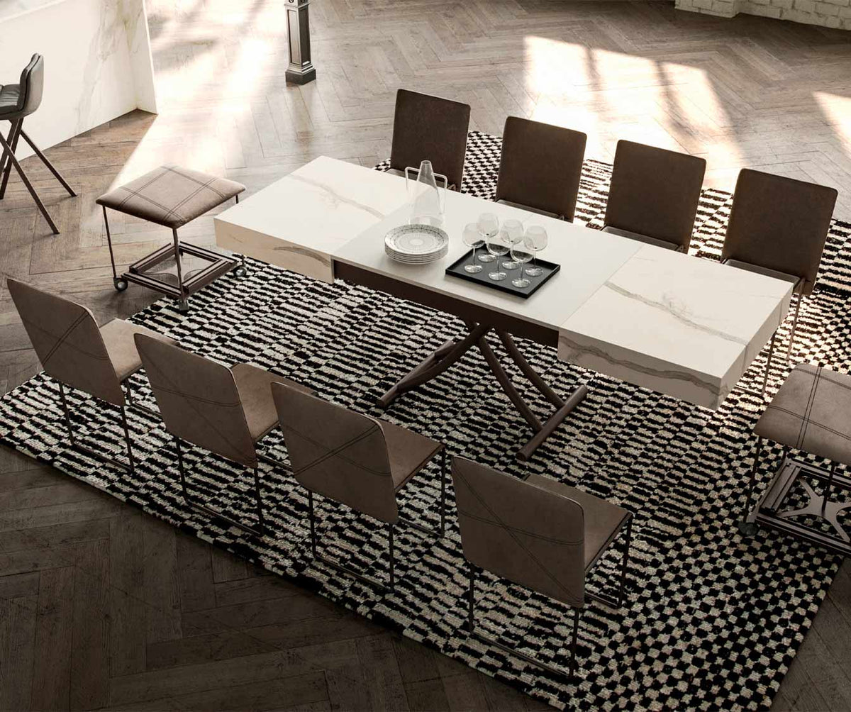 Table extensible moderne avec plateau en BOX Verre Extrachiaro, entourée de chaises élégantes dans un salon lumineux au sol en parquet et tapis à motifs noirs et blancs.