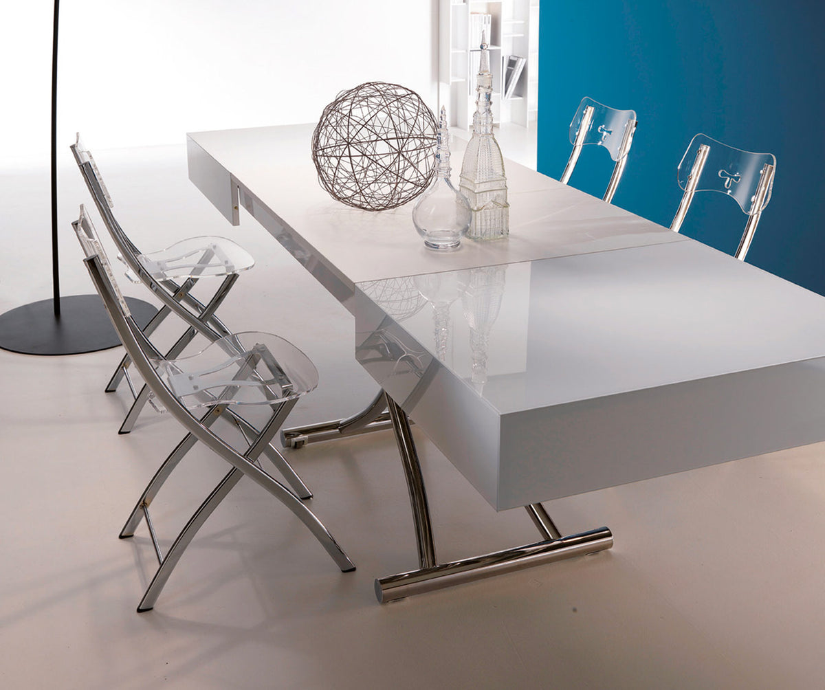 Table extensible moderne avec plateau en BOX Verre Extrachiaro blanc brillant, accompagnée de chaises transparentes design et décor minimaliste sur une surface claire.