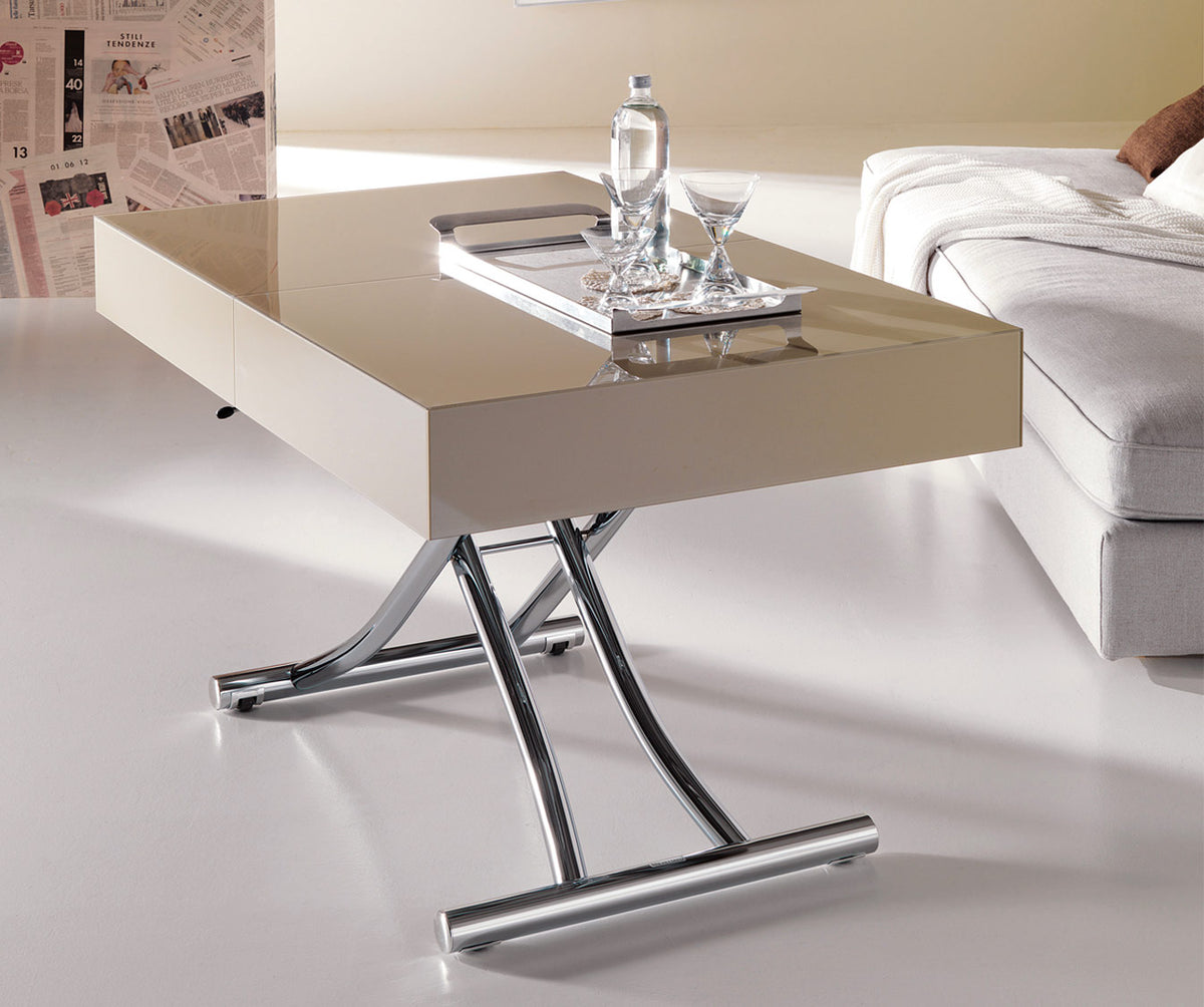 Table extensible moderne avec plateau beige brillant et piètement en métal chromé, mise en scène dans un salon lumineux à côté d'un canapé gris, modèle BOX Verre Extrachiaro.