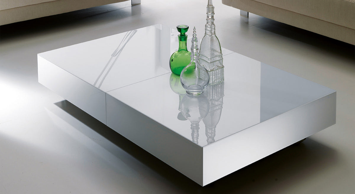Table basse design rectangulaire en BOX Verre Extrachiaro avec surface brillante et objets décoratifs en verre transparent et vert posés dessus.