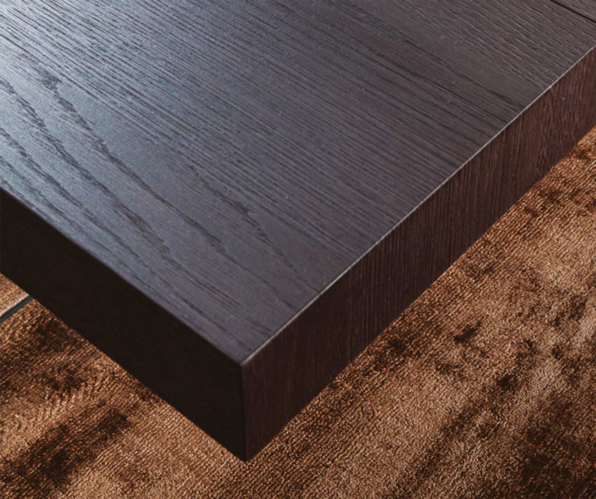 Plateau d'angle en bois sombre de la table extensible MARKUS Plaqué Rovere vecchio naturale, posé sur un tapis marron, illustrant la texture et la finition naturelle du bois.