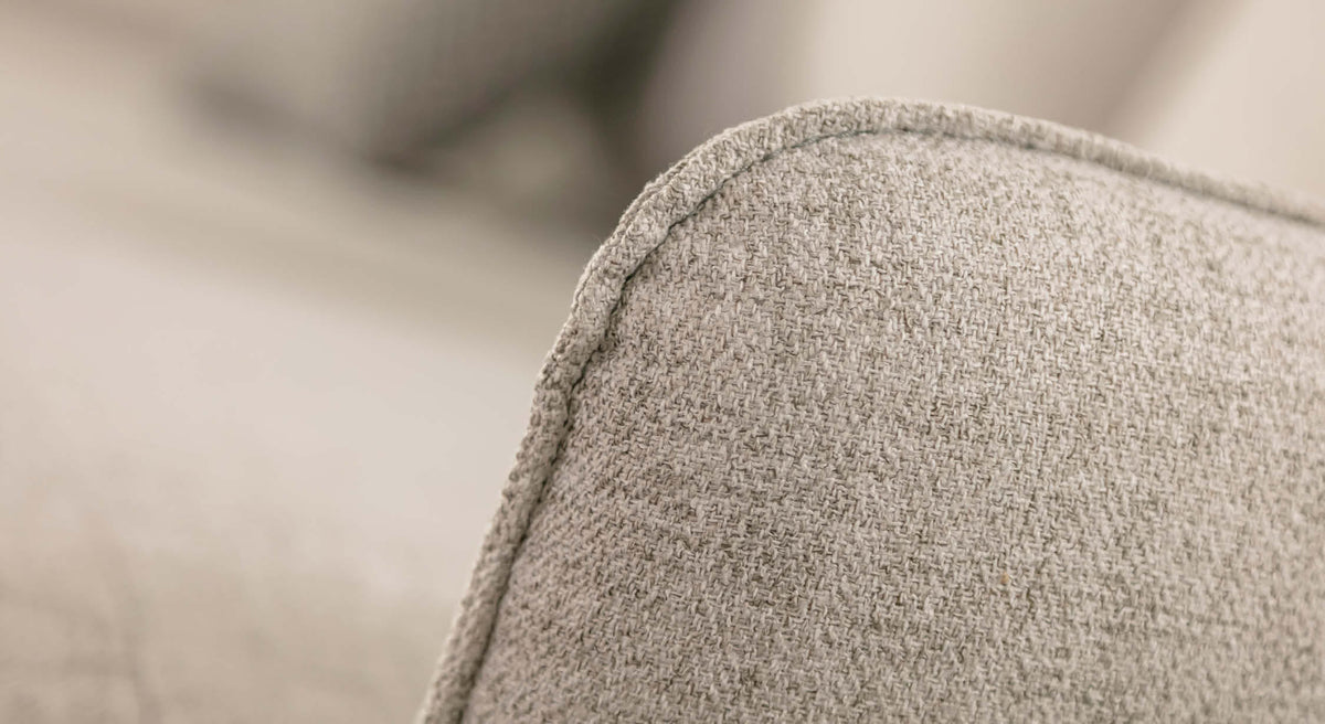 Gros plan sur l'accoudoir d'un canapé d'angle en tissu gris clair, modèle Bogart Foster Silver