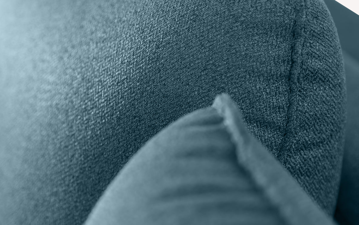 Gros plan sur le tissu bleu océan du canapé d'angle Bogart, revêtement détaillée et couture visible