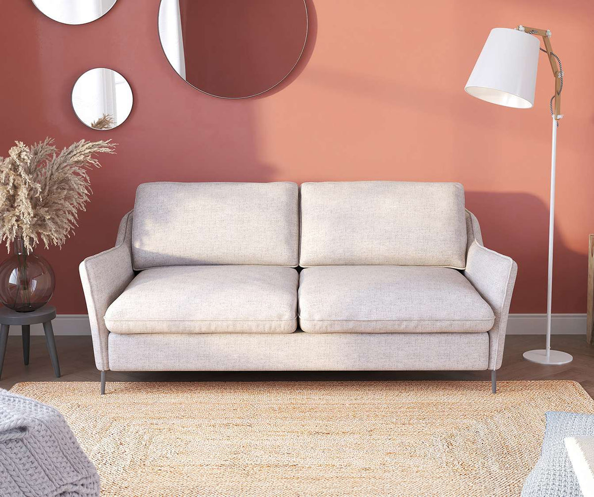 Canapé convertible BOGART Foster Silver en tissu gris clair, présenté dans un salon moderne avec décor naturel, idéal pour un couchage quotidien confortable.