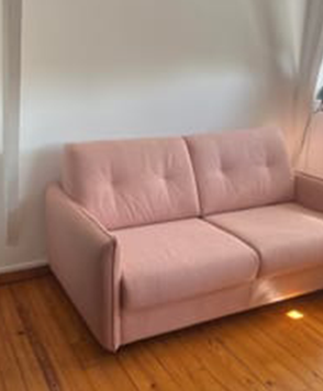 Le canapé convertible Tony en rose, dans un salon blanc