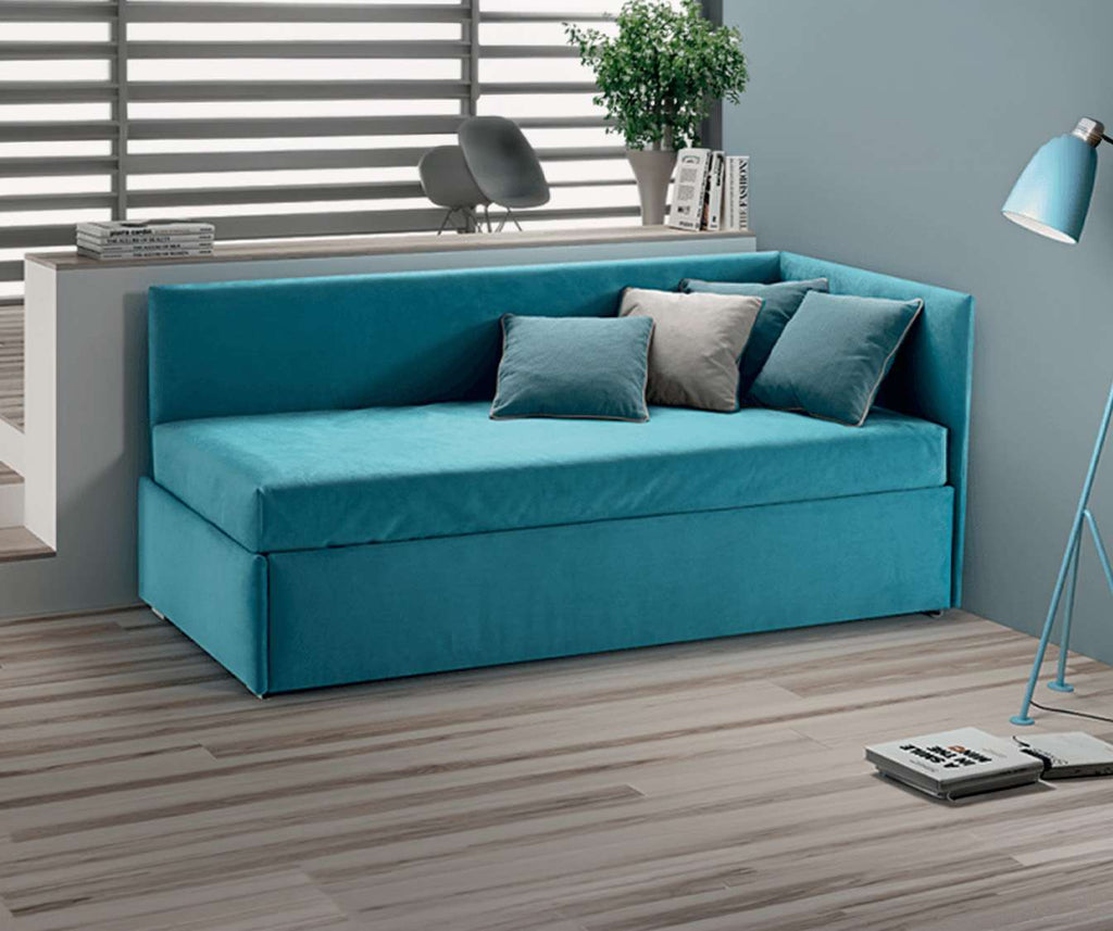 Lit gigogne ANGOLO 150 tissus au choix en tissu bleu, canapé compact avec coussins assortis dans un salon moderne, solution pratique pour couchage quotidien.