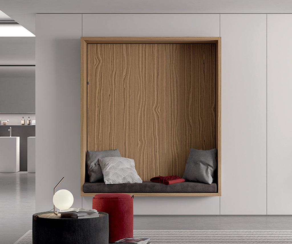 Espace cosy avec banquette intégrée dans un mur blanc, finition bois naturel, décorée de coussins gris et rouge, conçue dans la gamme ALCOVA +50 coloris & matériaux.