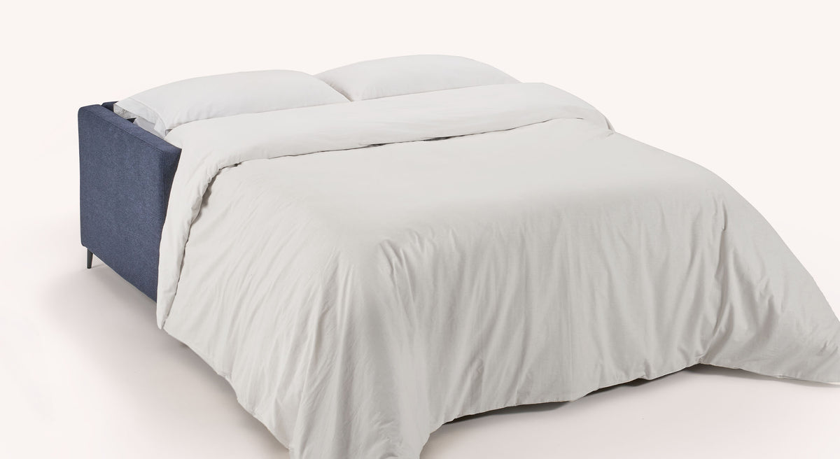 Canapé convertible AMY Austin Deep blue en tissu bleu profond, ouvert en grand lit avec couette blanche, idéal pour un couchage quotidien confortable.