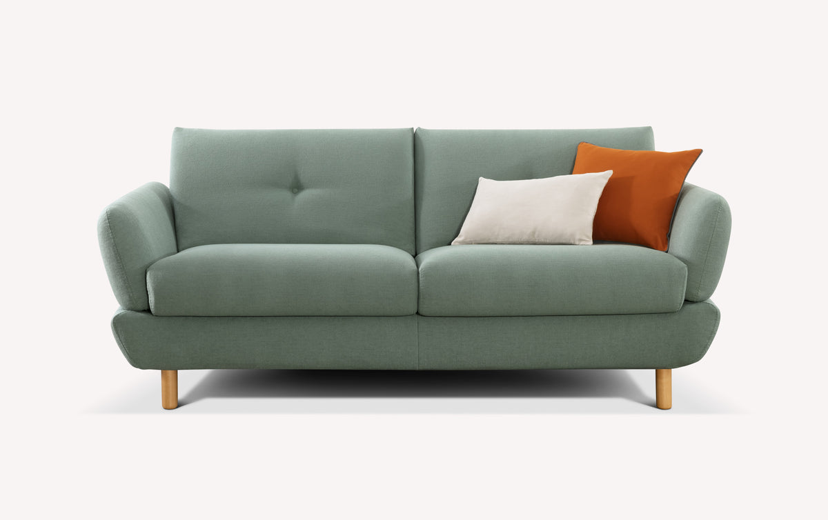Lot canapé et pouf FINN en tissu vert eucalyptus avec pieds en bois, accompagné de coussins beige et orange, idéal pour un séjour moderne et confortable.
