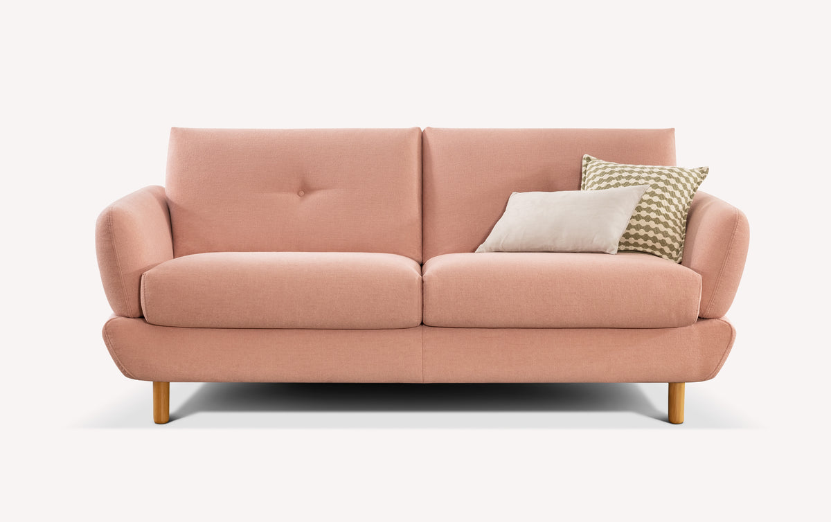 Canapé convertible rose en tissu, style moderne, avec deux coussins décoratifs, un beige et un à motifs géométriques