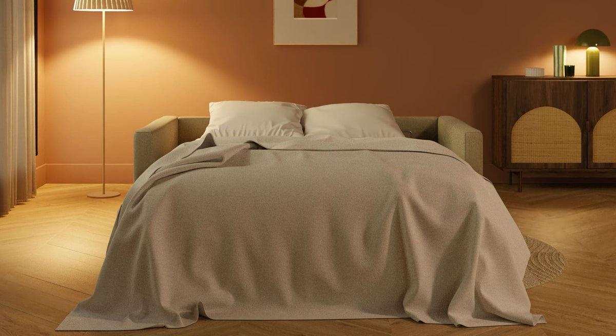 Canapé convertible JIMMY Foster Ivoire déplié en lit dans un salon chaleureux avec lampe sur pied et meuble en bois naturel, ambiance cosy et contemporaine.