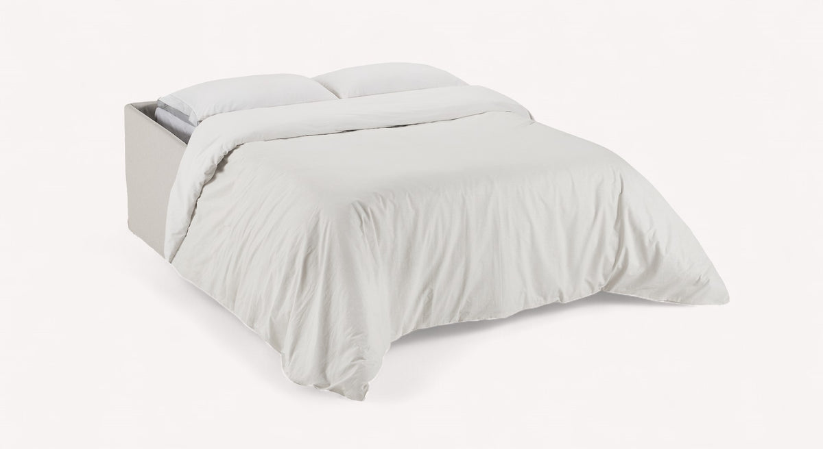 Canapé convertible ouvert en lit, tissu ivoire, modèle Lia, avec couverture et oreillers blancs
