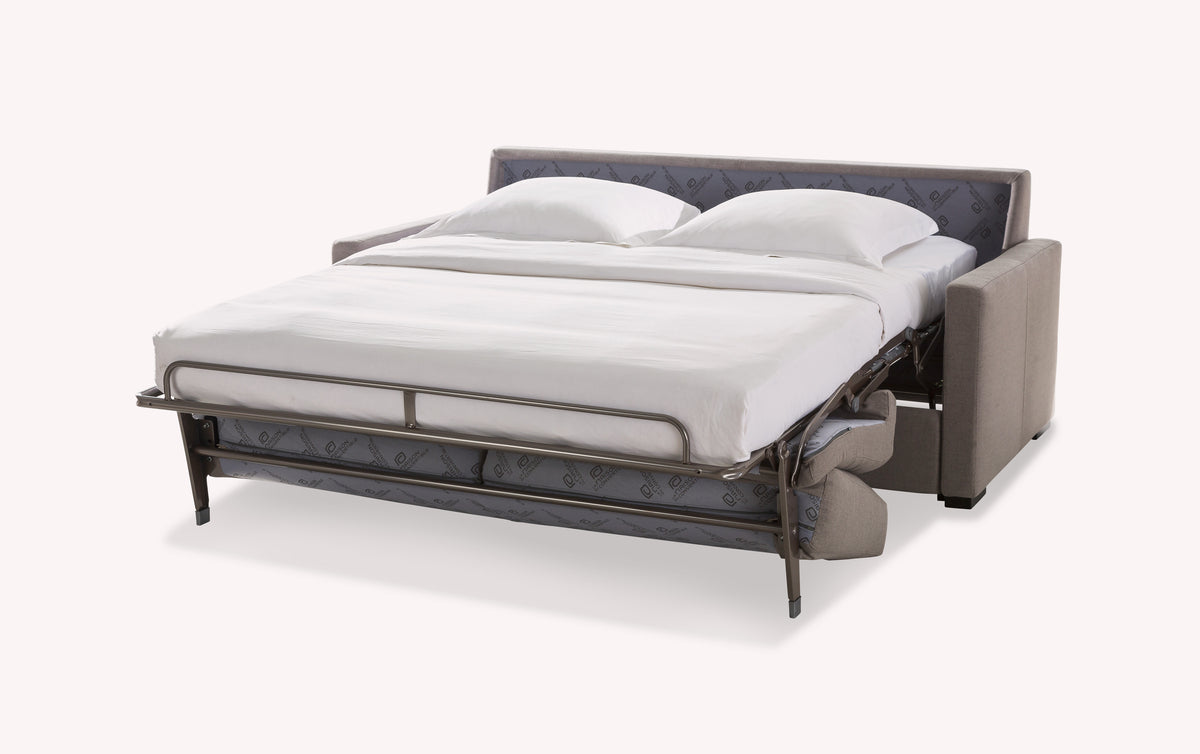 Canapé convertible gris ouvert en lit, avec matelas et coussins blancs, structure métallique visible