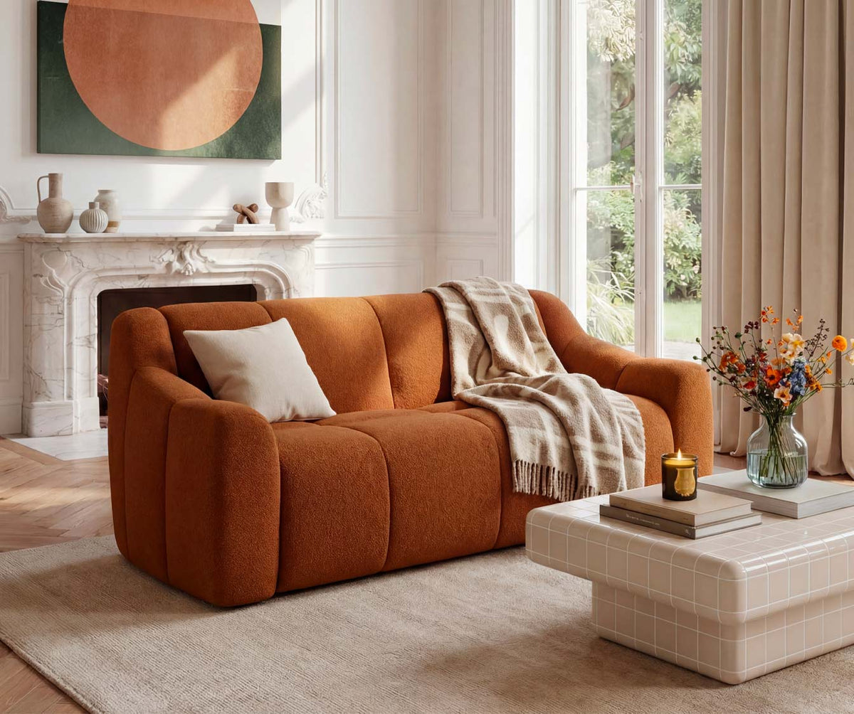 Canapé convertible MAMA Innuendo Cuivre en tissu cuivre avec coussin beige et plaid, intégré dans un salon lumineux au décor minimaliste et contemporain.