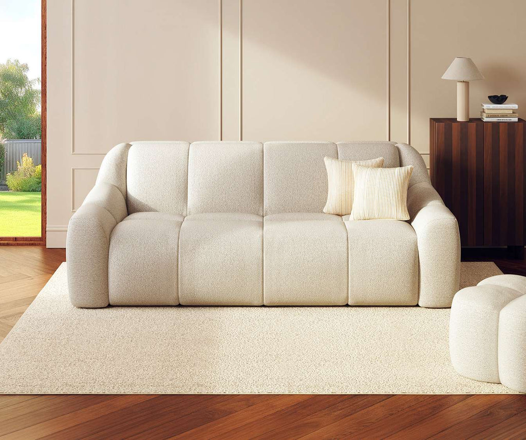 Canapé convertible MAMA Fixe Innuendo Ivoire en tissu ivoire, posé sur un tapis clair dans un salon lumineux avec parquet et meuble en bois foncé.
